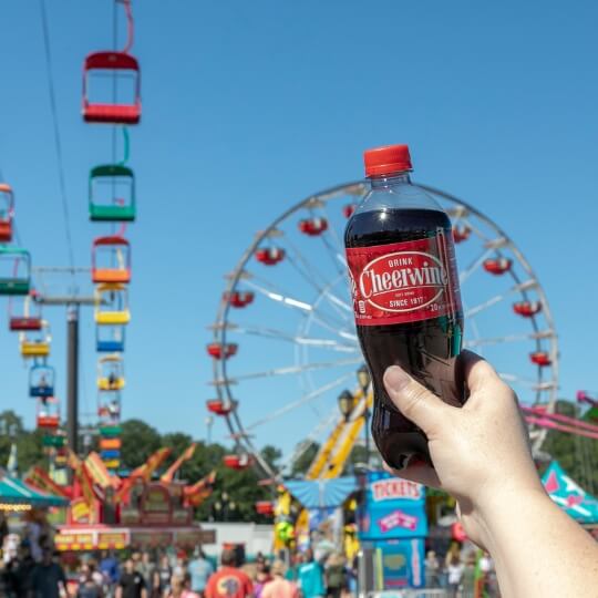 Cheerwine 20OZ bottle held up at a fair ground
